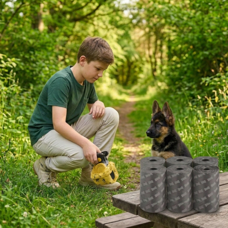 Ramasse crotte pour chien jaune avec six rouleaux de sacs gris et un garçon près d un berger allemand en forêt