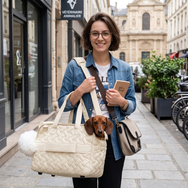Sac de transport pour chien beige porté par une femme devant une clinique vétérinaire